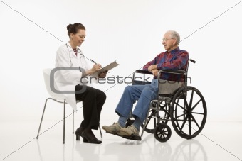 Doctor taking notes with an elderly man in wheelchair to her sid