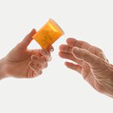 Close-up of female's hand handing medication bottle to elderly m