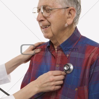 Female hands listening  to elderly man's heart with stethoscope.
