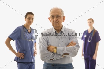 Elderly man in foreground with two nurses in background.