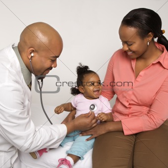 Mother holding baby for pediatrician to examine.