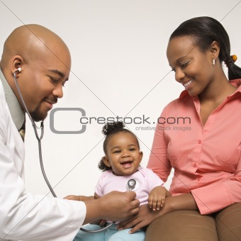Mother holding baby for pediatrician to examine.