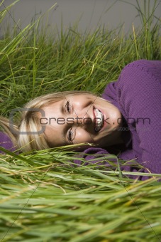 Caucasian woman lying in grass.