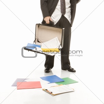 Businessman losing papers from briefcase.