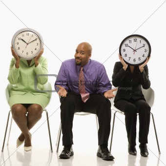Businesswomen covering faces with clocks and businessman shruggi