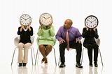 Businesswomen covering faces with clocks with businessman lookin