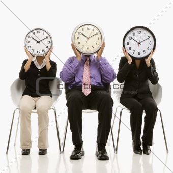 Business people covering faces with clocks.