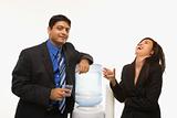 Businessman and businesswoman laughing at water cooler.