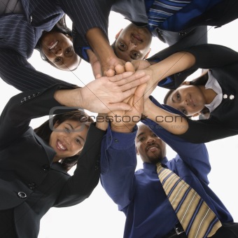 Diverse business people with hands in huddle.