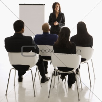 Businesswoman giving presentation in front of others.