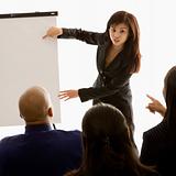 Businesswoman giving presentation in front of others.