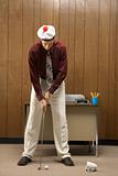 Retro businessman playing golf in office.