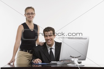 Woman standing beside man using computer.
