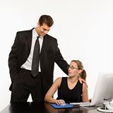 Man standing over woman at computer touching her shoulder innapp