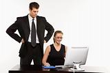 Man standing over woman at computer.