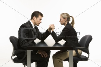 Man and woman arm wrestling on table.