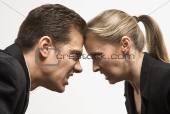 Angry man and woman with foreheads together staring at each othe