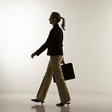 Silhouette of businesswoman walking with briefcase.