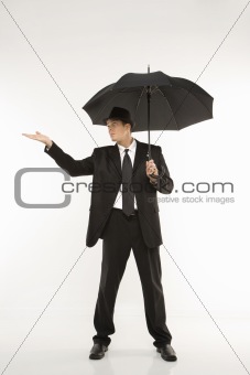 Businessman holding umbrella with hand held out.