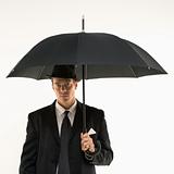 Businessman standing under umbrella.