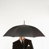 Businessman with face covered by umbrella.
