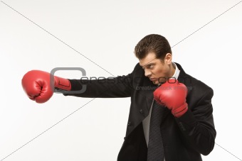 Man in suit wearing boxing gloves.