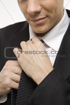 Close-up of man straightening necktie.