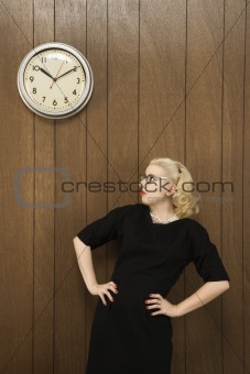 Woman looking up at clock on wall.