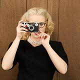 Woman holding a vintage camera up to her face.