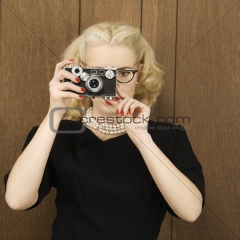 Woman holding a vintage camera up to her face.