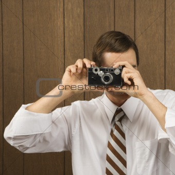 Man holding vintage camera up to his face.
