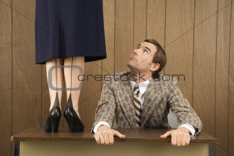 Man holding desk looking up to woman standing on desk.
