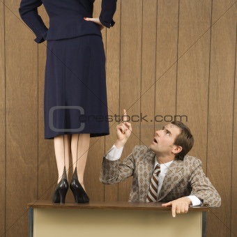 Man pointing up to woman standing on desk.