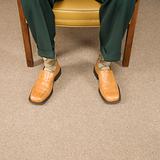 Close up of man sitting in chair wearing retro pants and shoes.