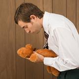 Man holding a stuffed animal preparing to kiss it.