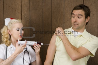 Female nurse giving man shot with giant syringe.
