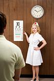 Female nurse pointing out eye chart to man.