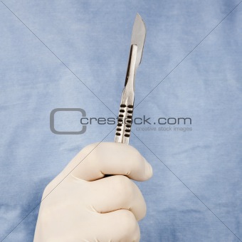 Male surgeon's hand holding scalpel.