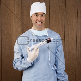 Male surgeon smiling holding giant syringe.