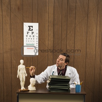 Male doctor at desk with figurine.