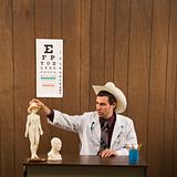Male doctor wearing cowboy hat playing with figurine.