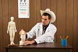 Male doctor wearing cowboy hat playing with figurine.