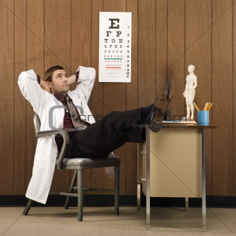 Male doctor with feet on desk.