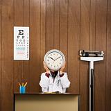 Doctor at desk holding clock over face.