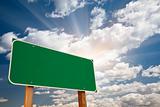Blank Green Road Sign over Dramatic Blue Sky with Clouds and Sunburst - Ready for your own message and Room For Copy on Clouds.