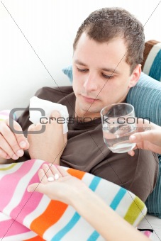 Sick man taking medicine on the sofa