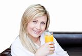 Smiling beautiful woman drinking orange juice in bedroom