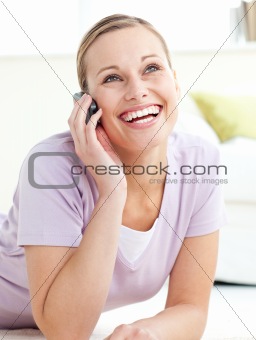 Delighted woman talking on phone lying on the floor 