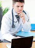 Worried male doctor using a laptop 