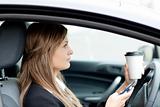 Blond businesswoman sending a text while driving